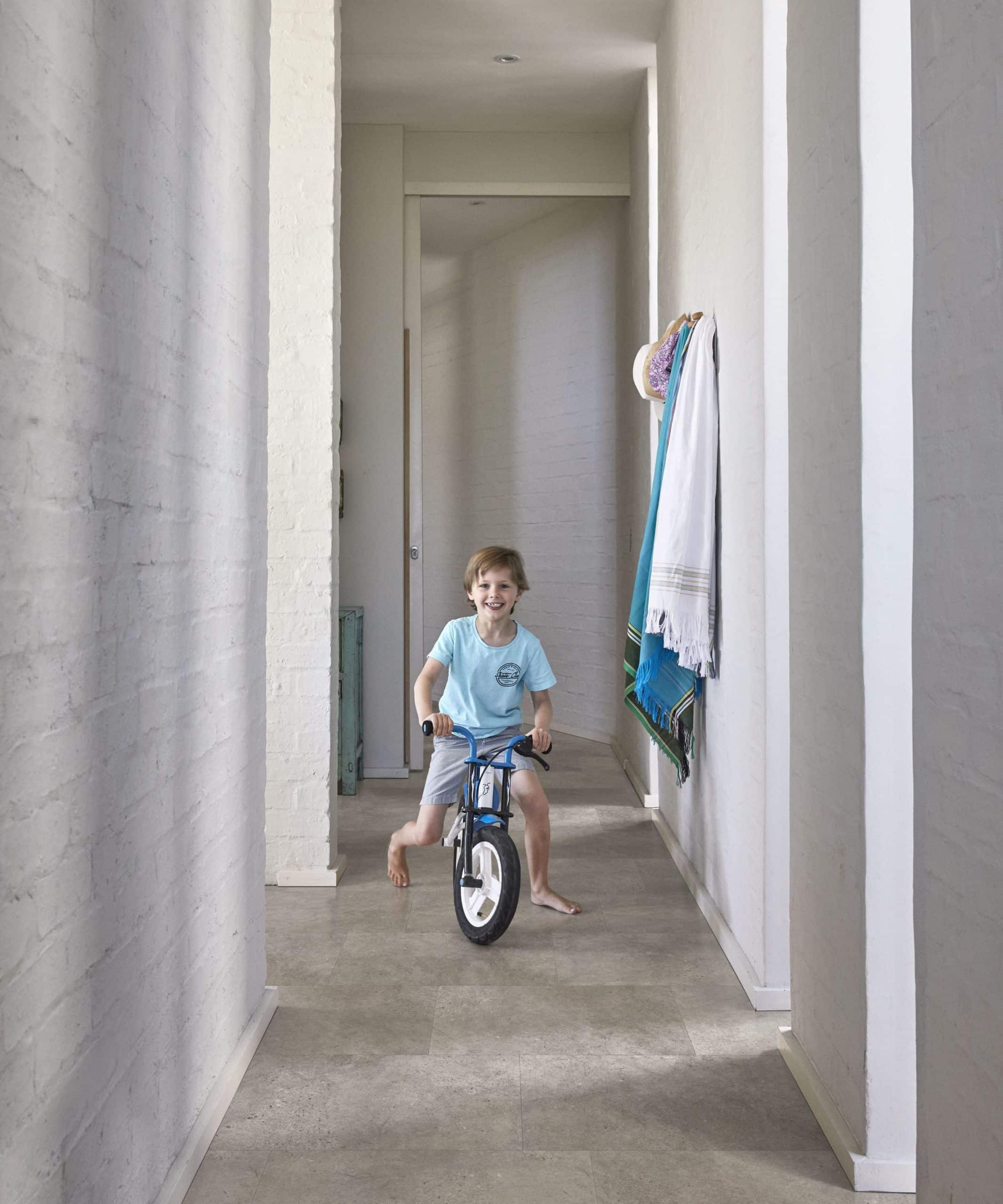 Enfant qui fait du vélo dans un couloir aux tons gris